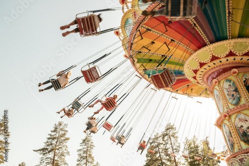 Kouvola, Finland - 18 May 2019: Ride Swing Carousel in motion in amusement park Tykkimaki and aircraft trail in sky.