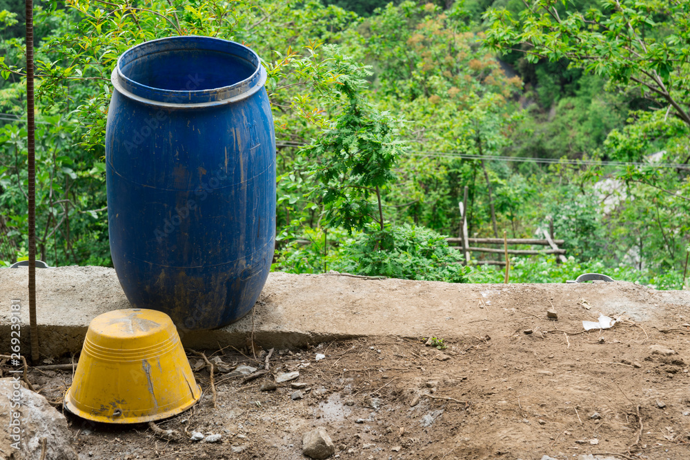 blue plastic trash bin and yellow metal bucket in garden, green background blue plastic trash bin and yellow metal bucket in garden, green background