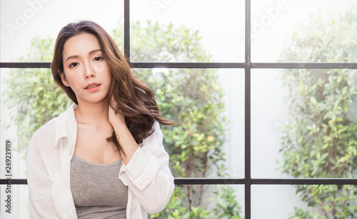 Portrait of young beautiful asian sexy woman relax over glass window. Smile happy asian girl  with perfect clear glow skin face looking. Lifestyle people beauty girl next door concept.