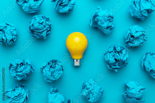 new idea concept with blue crumpled office paper and light bulb. top view of great business idea concept over blue background. creative solution during brainstorming session concept