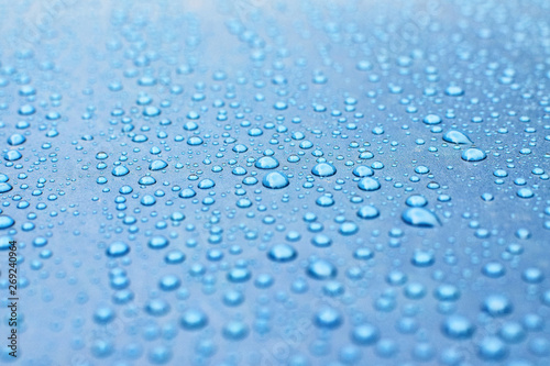 Drops of water on a blue surface. Beautiful macro shot of water bubbles or dews.