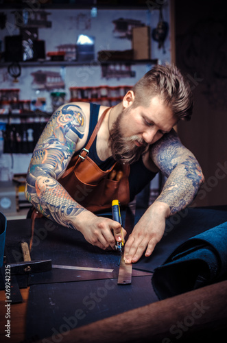 Currier of leather working on a new leather product in the tanner shop photo