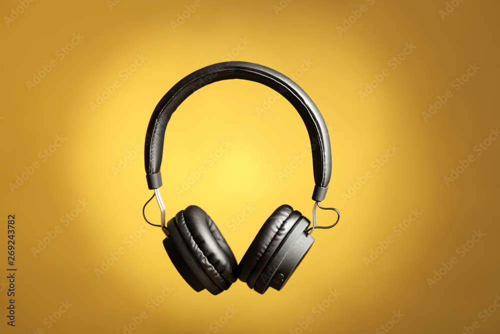 Stylish headphones with pads on color background