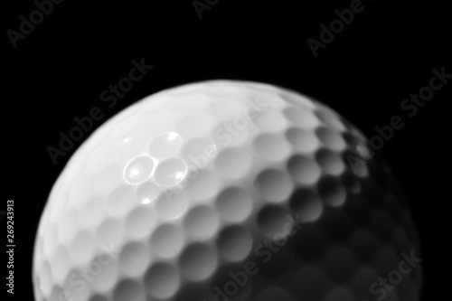 New golf ball against dark background, closeup