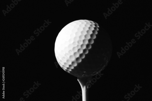 Golf ball on tee against dark background
