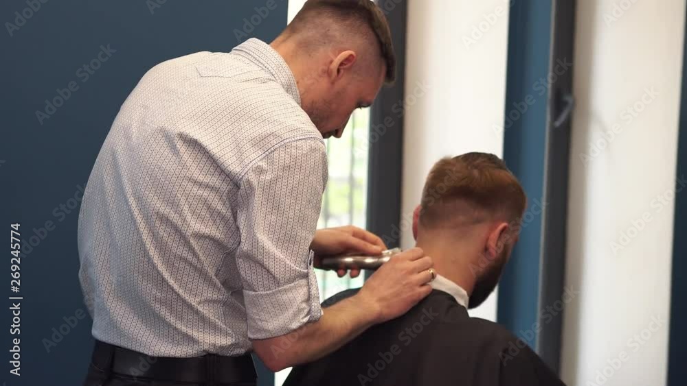 Close up shot of man getting trendy haircut at barber shop. Male hairstylist serving client, making haircut using machine and comb Close up shot of man getting trendy haircut at barber shop. Male hairstylist serving client, making haircut using machine and comb