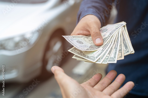 Business man holding money in hand stand front car prepare pay by installments - insurance, loan and buying car concept