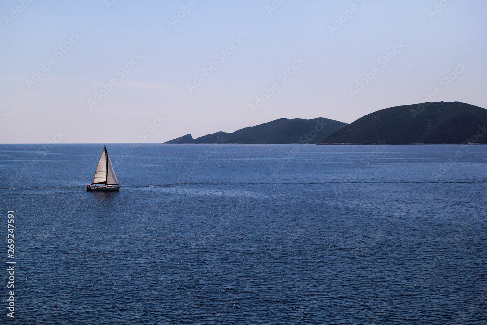 Lonely ship, sailboat at open sea. Calm sea allows best sailing in peaceful scene. Little sailing boat on turquoise sea. Beautiful view, natural environment. Summer season, travel, vacation, holiday.