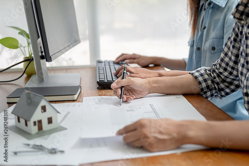 Engineers discuss a blueprint while checking information on a tablet computer in a office.