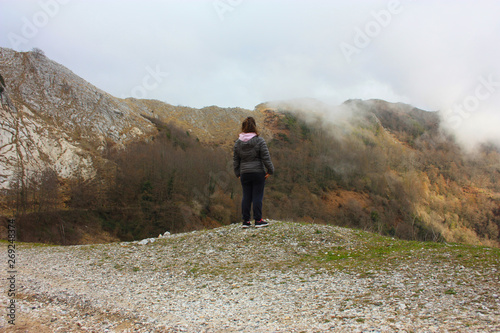 girl walks alone in the mist and fog along the paths of the Apuan Alps in Tuscany