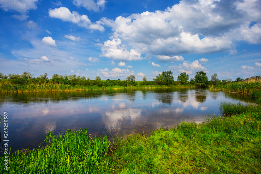 beautiful summer river scene with cumulus clouds reflected in a water