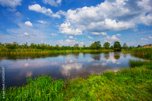 beautiful summer river scene with cumulus clouds reflected in a water