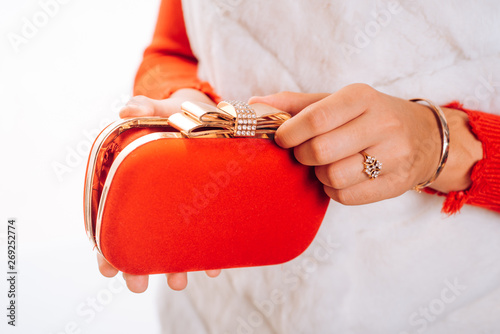 Carry your lippy in style. Mini bag. Fashion handbag. Fashion accessory. Vintage or retro clutch design. Red purse or pouch. Box clutch. Hand bag designed with rhinestones. Clutch bag in female hands photo