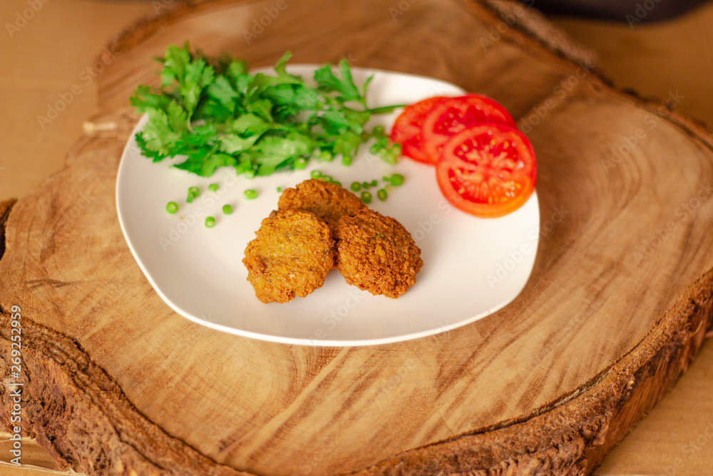 Falafel Closeup on Old Wooden Log, with Green Parsley and Tomato Falafel Closeup on Old Wooden Log, with Green Parsley and Tomato
