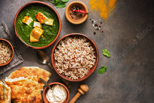 Indian food. Palak paneer or Spinach and Cottage cheese curry, rice, spices , naan, on a dark background. Top view, copy space.