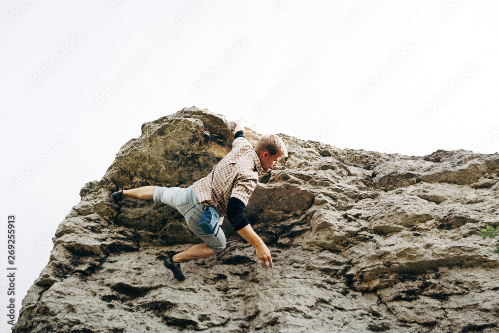 Brave young man climbs the top of the cliff