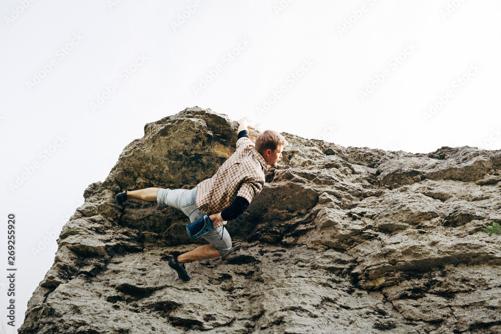 Brave young man climbs the cliff Brave young man climbs the cliff