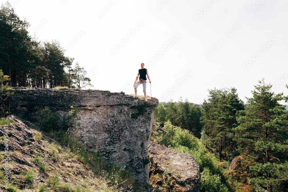 Rock climber standing at the edge of the cliff with a rope