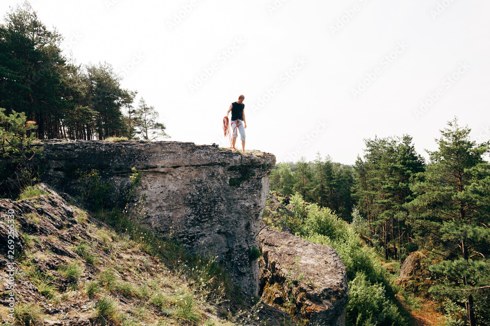 Rock climber standing at the edge of the cliff with a rope