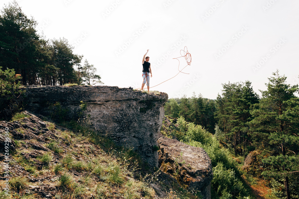 Rock climber standing at the edge of the cliff with a rope