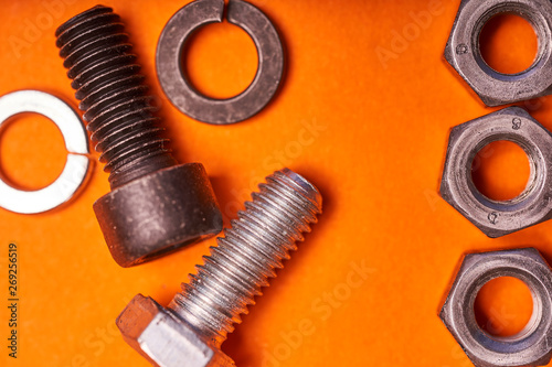 Bolted connecting elements on orange background close-up