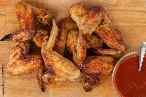 Chicken wings with red sauce on wooden table