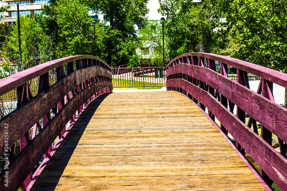 Walking Bridge Over River In Park Setting