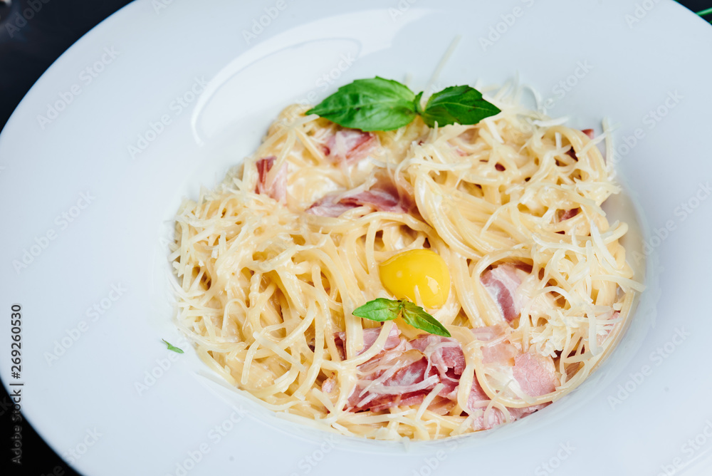 Pasta alla carbonara. Traditional italian dish spaghetti carbonara with bacon in a cream sauce in a white plate close up. Space Pasta alla carbonara. Traditional italian dish spaghetti carbonara with bacon in a cream sauce in a white plate close up. Space