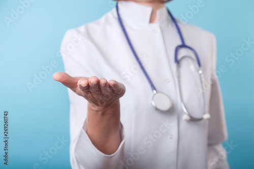 Close-up of doctor senior woman holding something in empty hand over blue background