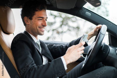 Businessman ignoring safety and texting on mobile phone while driving © Minerva Studio