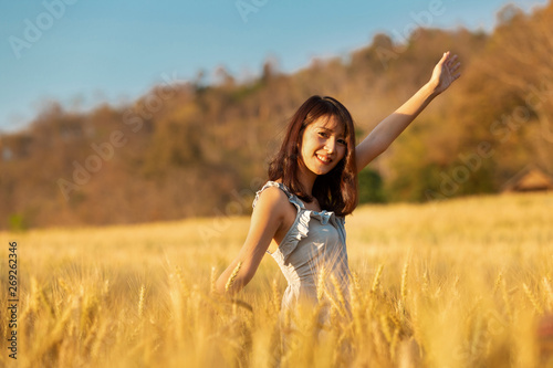 Beautiful and happy asian woman enjoying life in barley field at sunset.
