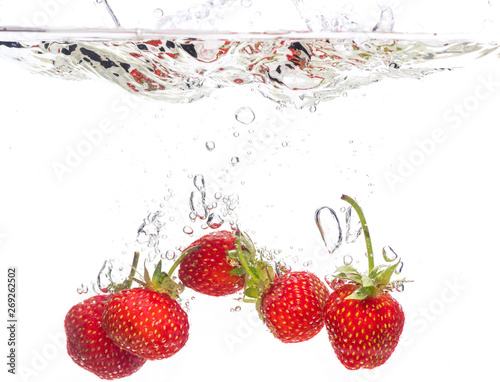 Red fresh strawberries thrown into the water, under water. Spat and splash