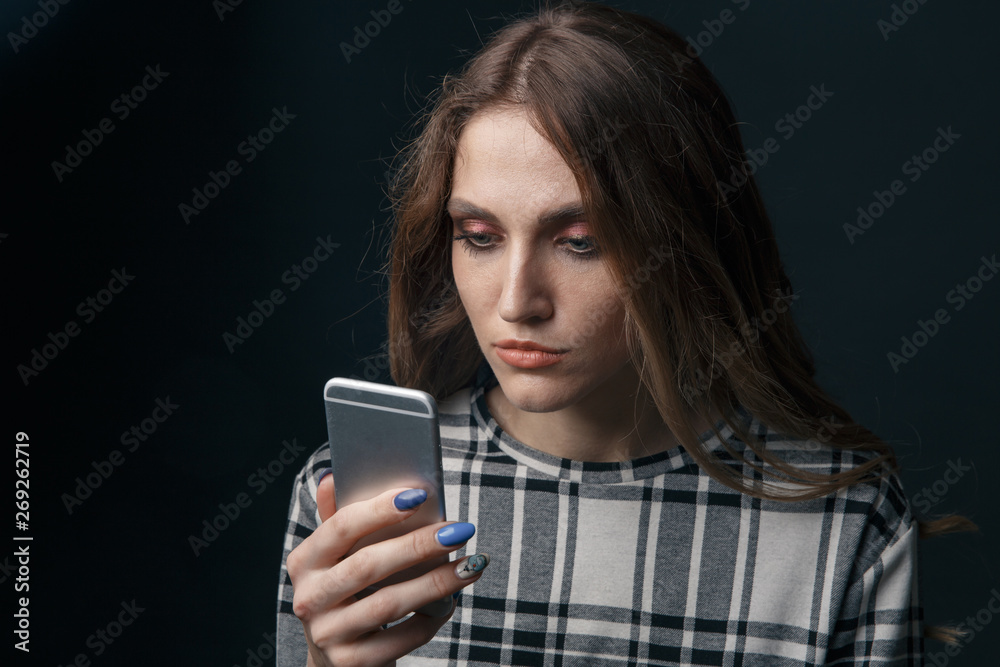 Sad teen being victim of cyber bullying online sitting on a couch in the living room at home Sad teen being victim of cyber bullying online sitting on a couch in the living room at home