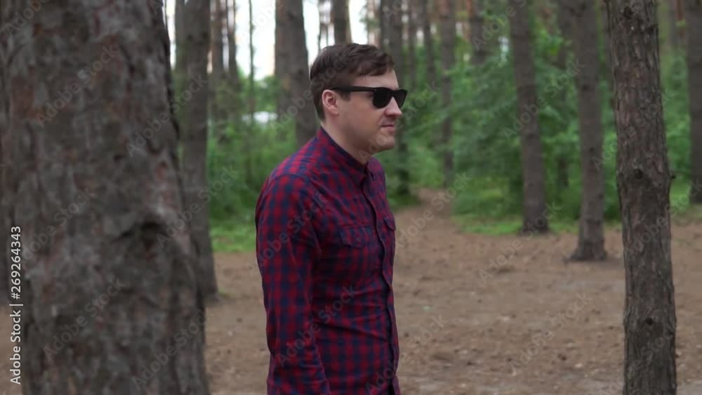 Young man walking on path in forest, summer day. Portrait of young man in casual clothes, walking along path in quiet autumn park Young man walking on path in forest, summer day. Portrait of young man in casual clothes, walking along path in quiet autumn park