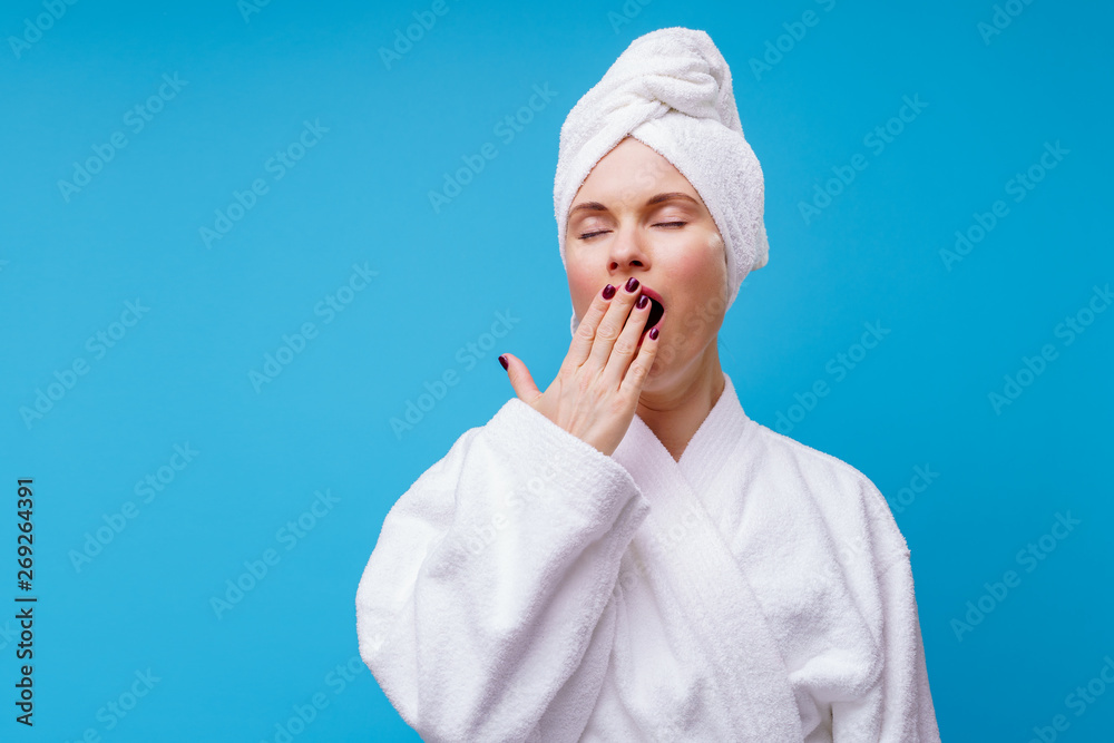 Photo of yawning woman in white coat and towel on head Photo of yawning woman in white coat and towel on head