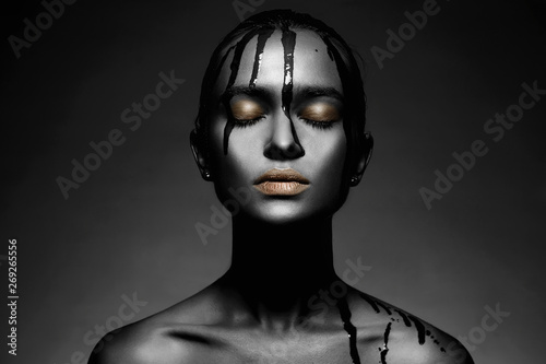 Young woman in black paint with golden lips