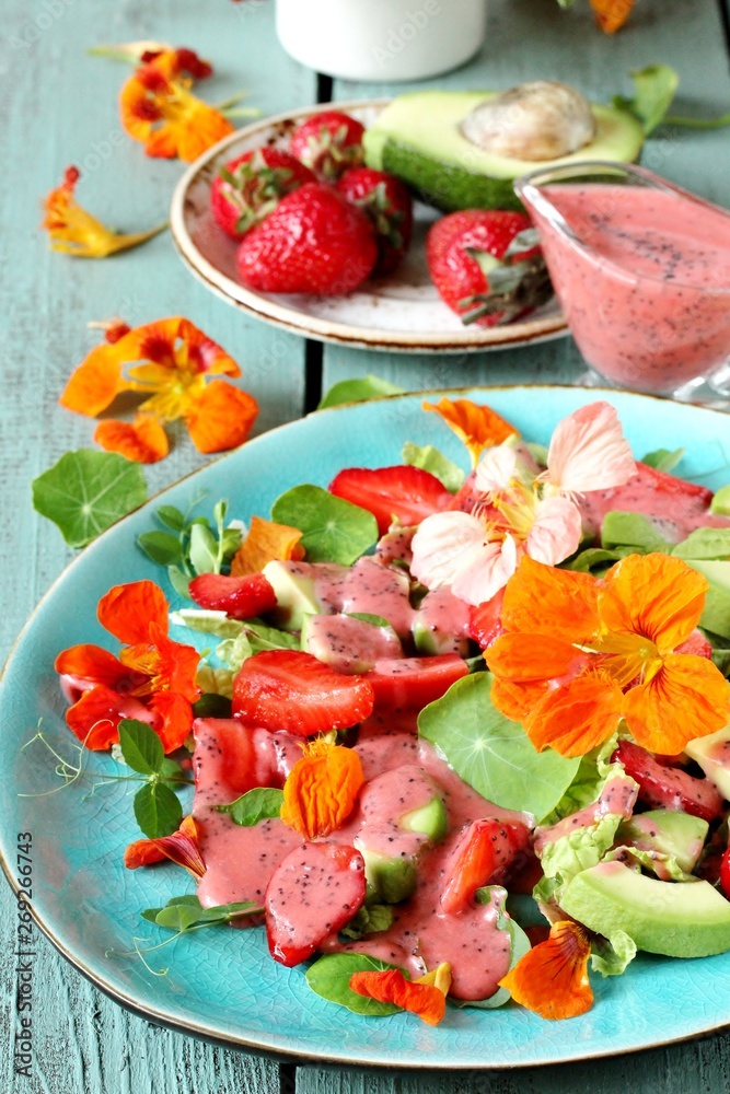 salad with nasturtium flowers and leaves with strawberries and avocados. dressed with strawberry vinaigrette or strawberry dressing with poppy seeds. bright summer salad with edible flowers. salad with nasturtium flowers and leaves with strawberries and avocados. dressed with strawberry vinaigrette or strawberry dressing with poppy seeds. bright summer salad with edible flowers.