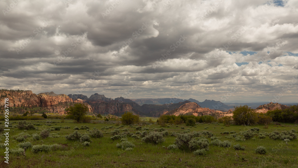 Patches of sunlight illuminate parts of the distant mountains in a southwest desert landscape.