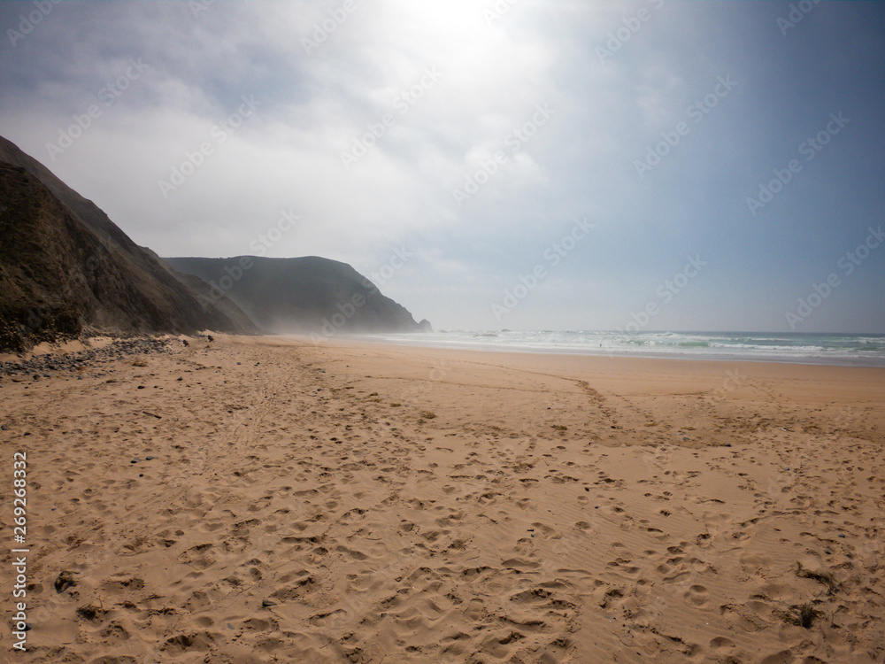 Praia de Castelejo beautiful beach for surfers on west coast of Portugal. Coast of Atlantic ocean amidst mountains Praia de Castelejo beautiful beach for surfers on west coast of Portugal. Coast of Atlantic ocean amidst mountains