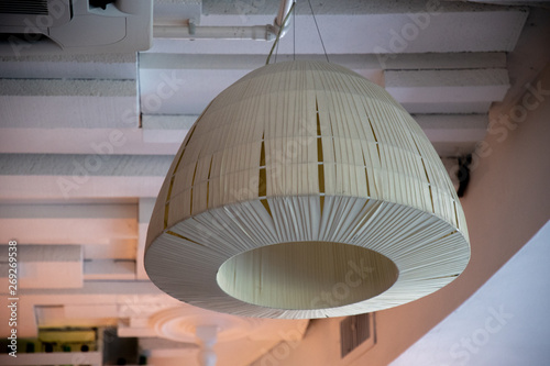 Simple white lampshade of minimal style ceiling lamp. Geometric 3D shape on textured wooden planks background.