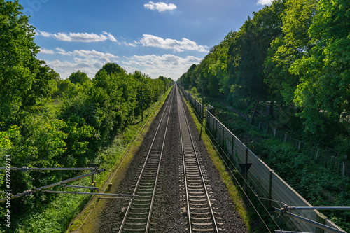 Bahn Gleise, Schienen führen gerade zum Horizont bei blauem Himmel durch grüne Natur