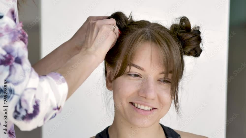 hair stylist makes a young beautiful caucasian brunette's hairstyle. Medium plan, natural lighting hair stylist makes a young beautiful caucasian brunette's hairstyle. Medium plan, natural lighting