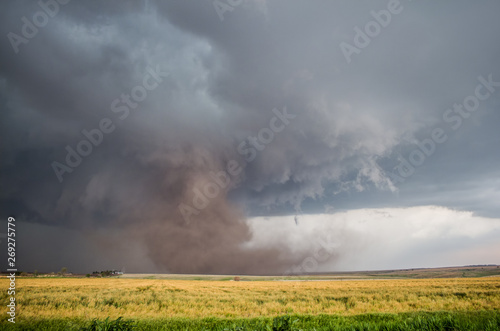 A large tornado fills the air with a huge cloud of dust under a supercell storm.