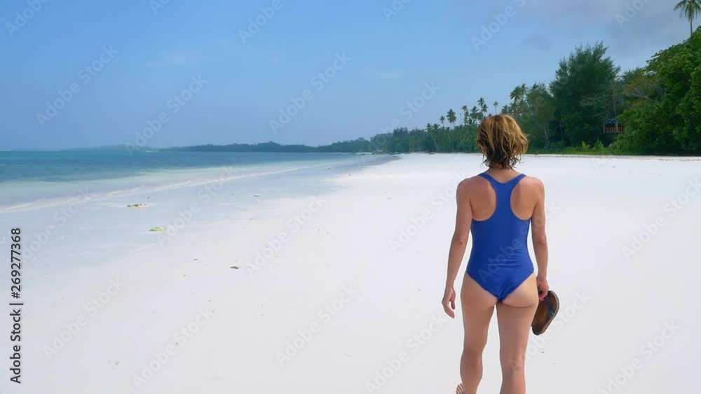 Slow motion: woman walking on white sand beach turquoise water tropical coastline Pasir Panjang Kei Islands Indonesia Moluccas Maluku Indonesia travel destination sunny hot day Slow motion: woman walking on white sand beach turquoise water tropical coastline Pasir Panjang Kei Islands Indonesia Moluccas Maluku Indonesia travel destination sunny hot day