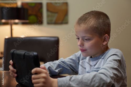 Boy using tablet indoors to learn. 