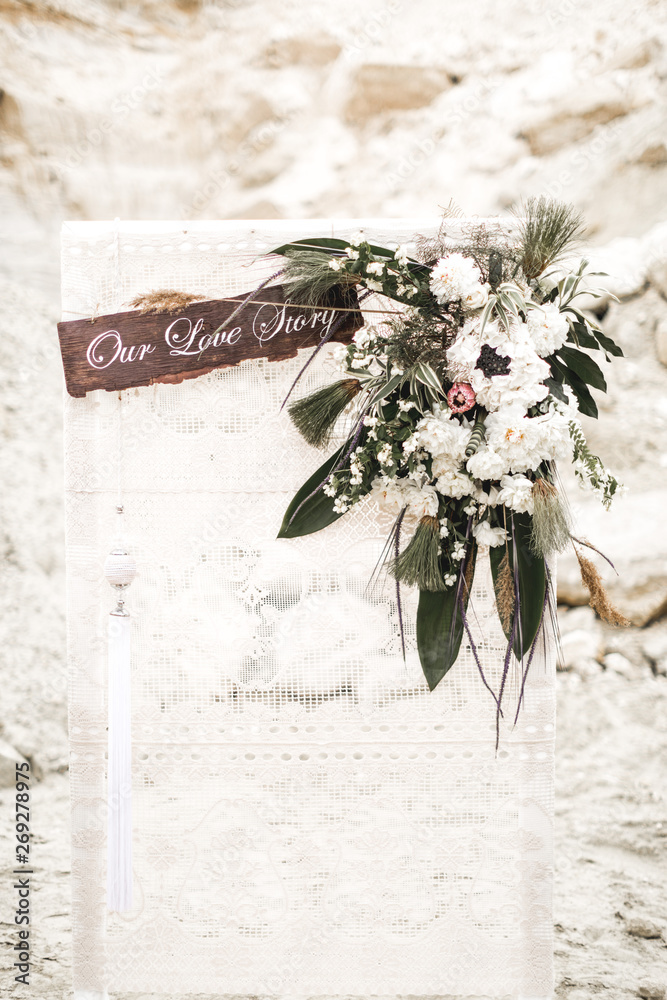 Romantic rustic wedding ceremony in desert. wooden arch with white cloth and flowers. Boho wedding ceremony