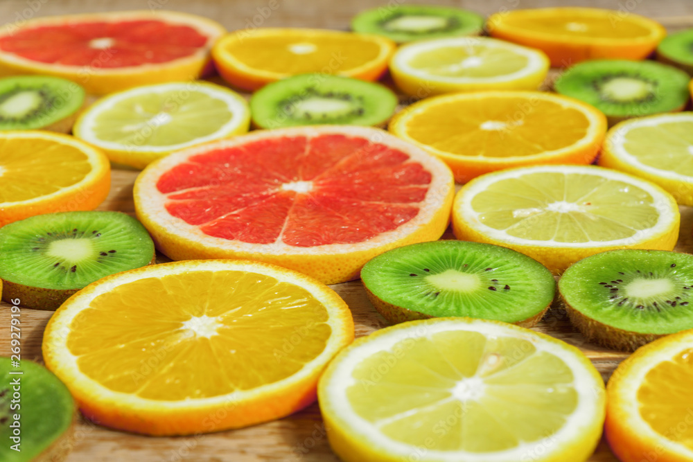 Fototapeta premium slices of oranges, lemons, kiwi, grapefruit pattern on wooden background. Fruit summer background