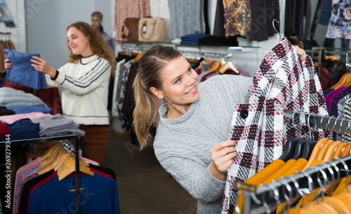 Women choosing warm coats in boutique