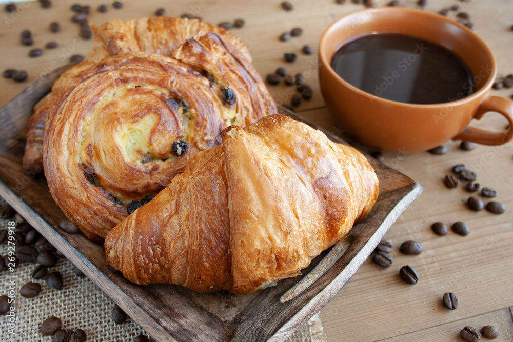 Sweet breakfast: black coffee, croissants and a roll with raisins