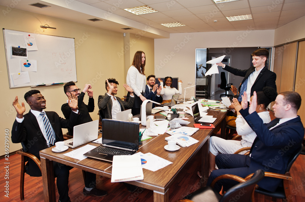 Multiracial business team meeting around boardroom table, two team leaders throw paper up. Multiracial business team meeting around boardroom table, two team leaders throw paper up.